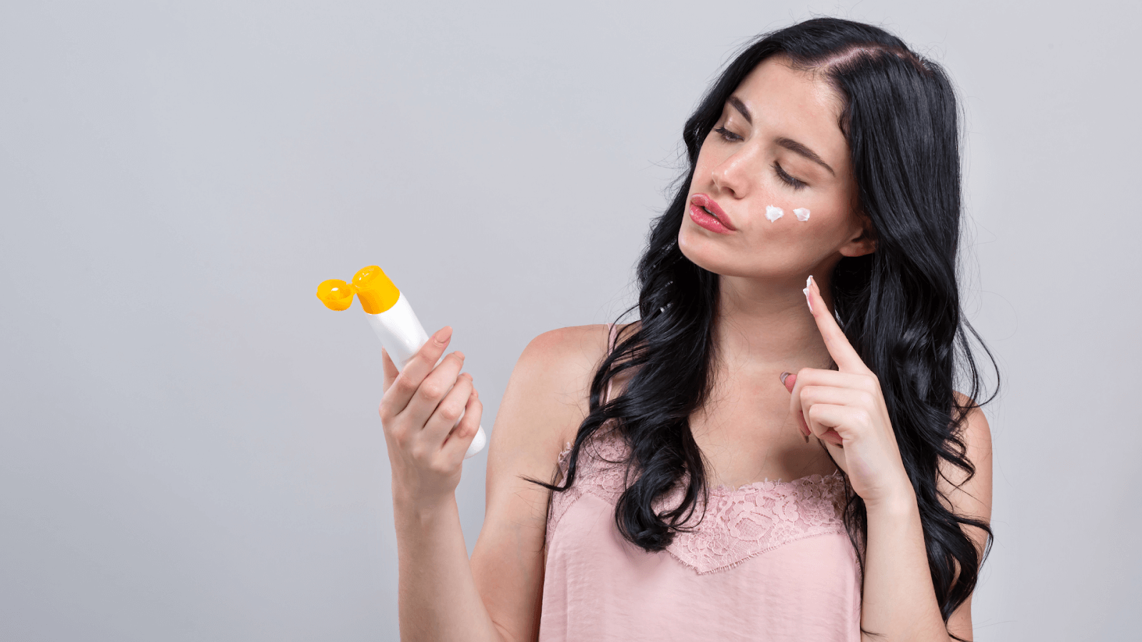 Girl applying sunscreen to face